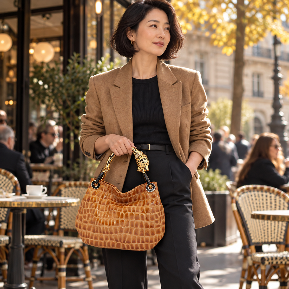 Woman carrying the INGA tan croco-embossed leather medium handbag with jaguar sculpture handle, styled for autumn.