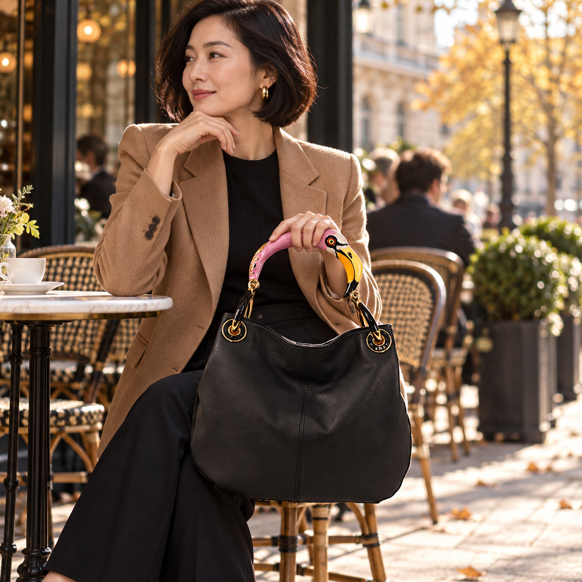 Woman carrying the INGA black leather medium handbag with flamingo sculpture handle, styled for autumn.