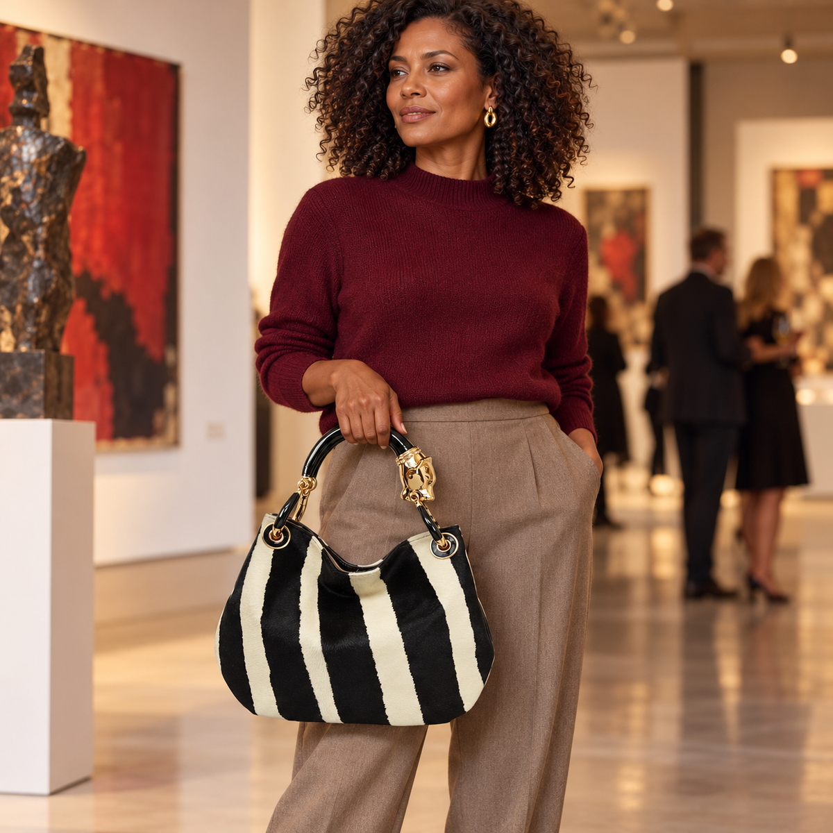 Woman carrying the INGA black and ivory zebra-print pony hair medium handbag with black panther sculpture handle, styled for autumn.